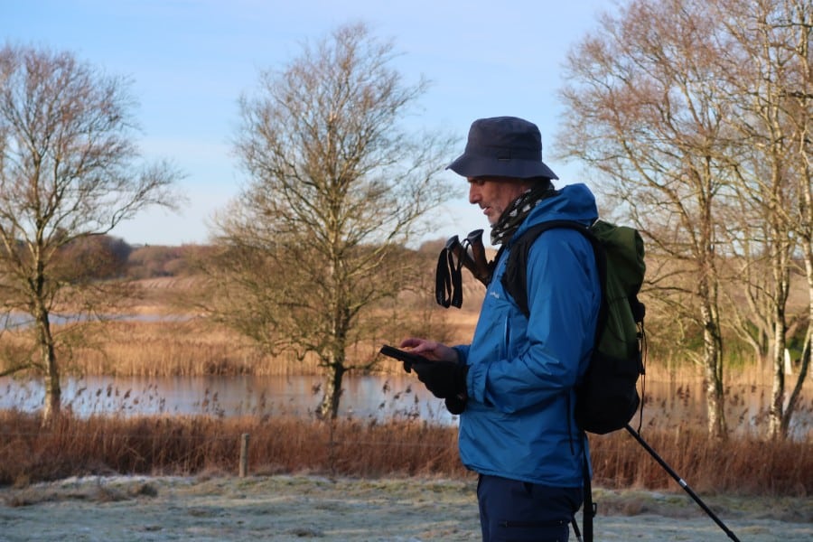Vandrer tjekker kort på mobilen ved Halkær Mølle.